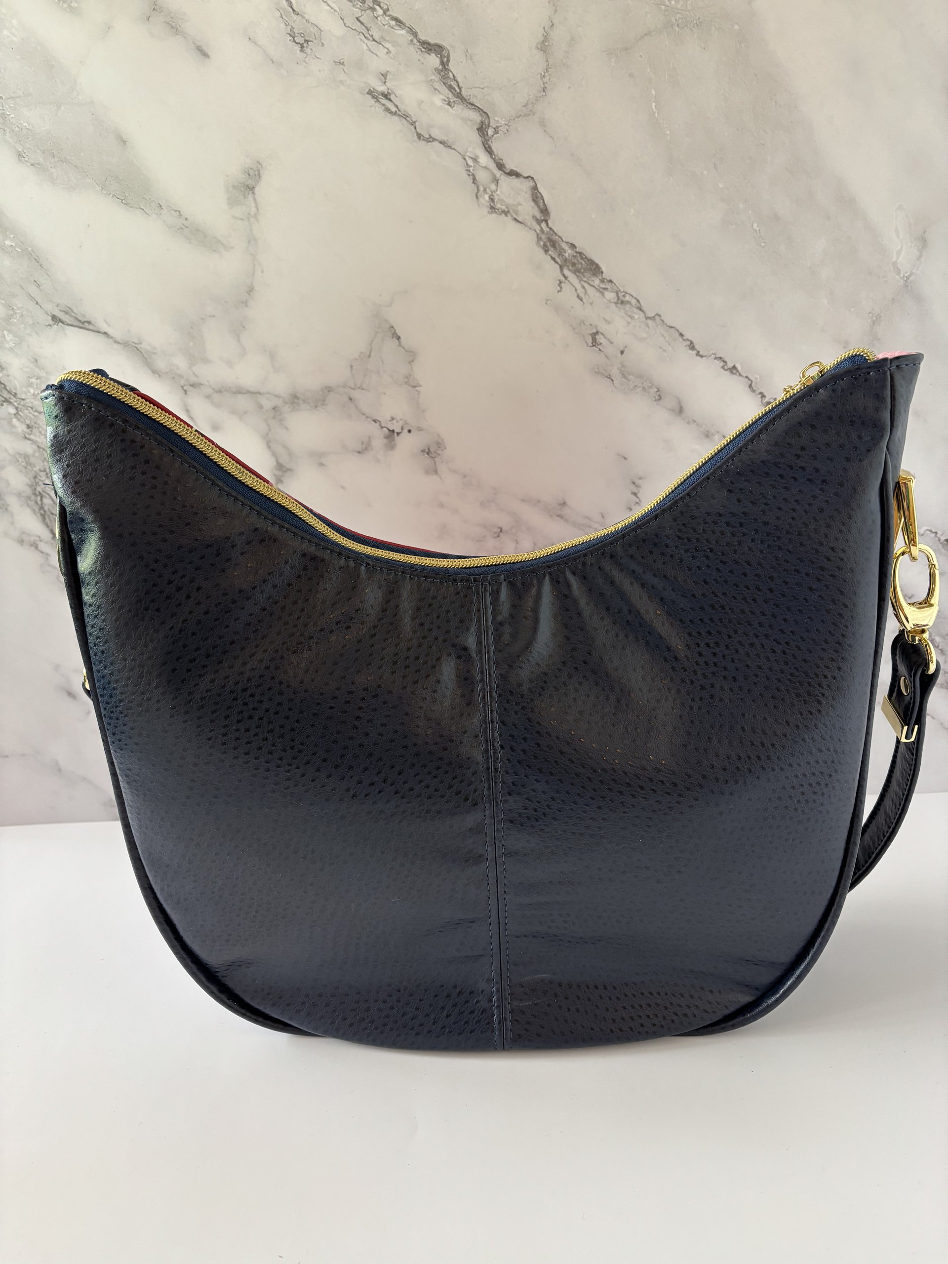 Curved semi-slouchy handbag with matching eyewear/sunglass case, in a floral pattern in cream, pink, and maroon tones, with a rich solid navy