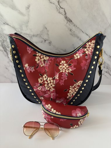 Curved semi-slouchy handbag with matching eyewear/sunglass case, in a floral pattern in cream, pink, and maroon tones, with a rich solid navy